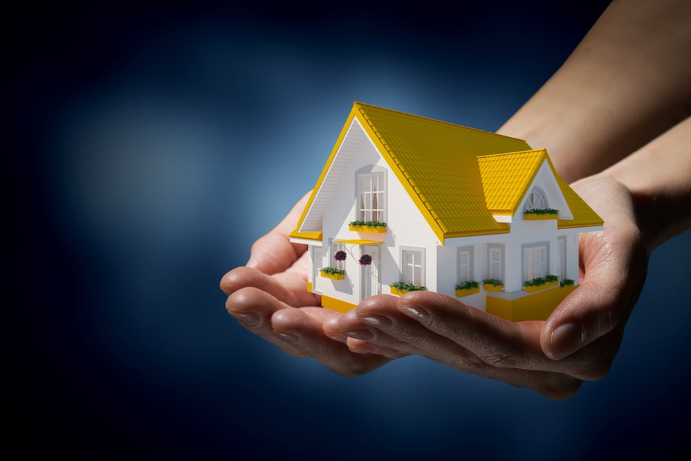 Human hands holding model of dream house Human hands holding model of dream house